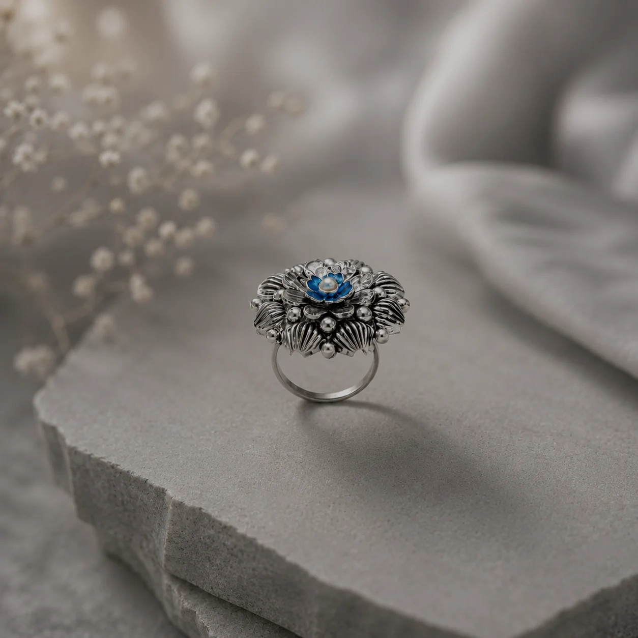 Ornate handcrafted silver floral cocktail ring with a blue centre stone, from the silver jewellery under ₹5,000 edit